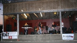 Indoor stage area with musical instruments, brick walls, and an “EXIT 13” sign near the front.